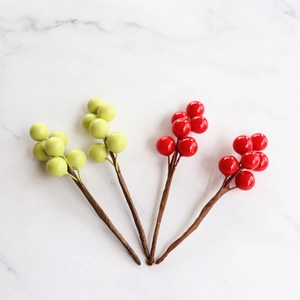 Flat lay of artificial red and green berries on white marble for festive home decor