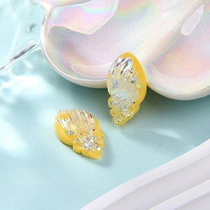 Close-up of yellow resin conch shell charms with clear faceted crystal inlay for DIY crafts
