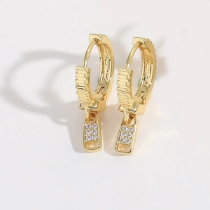Macro detail of gold-plated zipper pull earrings featuring sparkling white zircon stones