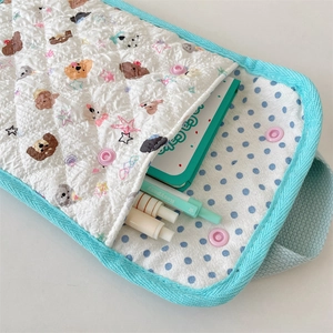 Detailed view of quilted cotton wristlet bag featuring cartoon dog patterns and snap closure