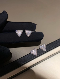 Close-up of sparkling triangle zircon stud earrings on display with elegant lighting
