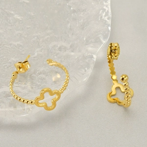 Elegant golden stainless steel clover stud earrings on a rippled glass tray