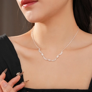 Silver bow pendant necklace shown on a model neck with elegant floral curve details
