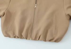 Détail d'une veste courte kaki avec fermeture éclair en métal et ourlet élastique