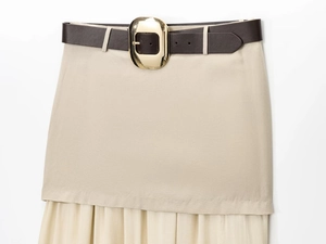 Detail de la jupe midi beige avec ceinture en similicuir marron et grande boucle doree