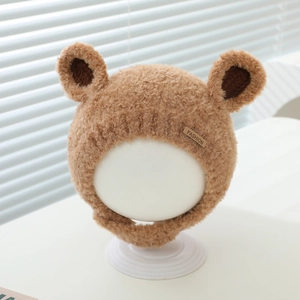 Detail of warm plush baby winter hat with bear ears and fashion label in caramel brown