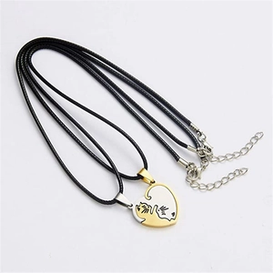 Detail of interlocking heart pendants with gold and silver cat silhouettes on black cords
