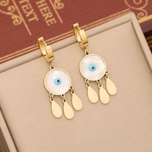 Detail of gold evil eye earrings with blue enamel and white shell on jewelry display pad