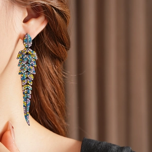 Gros plan de boucles d'oreilles plume vintage avec glands en strass colorés sur modèle