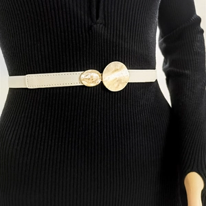 Detail of white elastic waist belt with double gold circular metal buckles on black dress