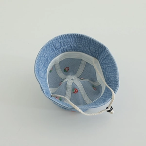 Detail of baby denim bucket hat showing red strawberry embroidery and windproof strap