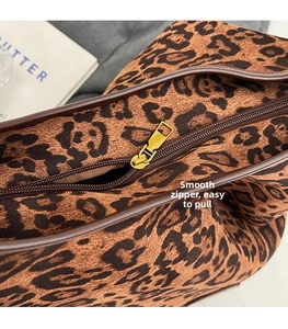 Close-up of golden zipper detail and leopard print fabric on a large tote bag