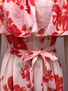 Detailansicht eines roten Blumen-Chiffonkleids mit Volant-Ausschnitt und Bindegürtel