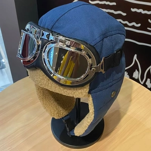 Detail of blue aviator trapper hat with silver goggles and warm beige faux fur lining