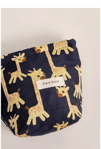 Close-up of jacquard fabric detail on navy giraffe cosmetic bag with H&R brand label