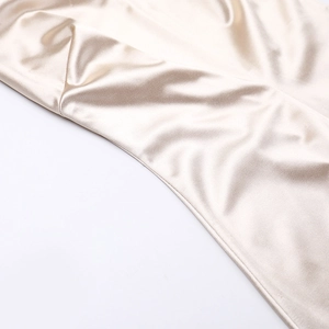 Gros plan sur un tissu satiné champagne luxueux montrant un drapé élégant et soyeux