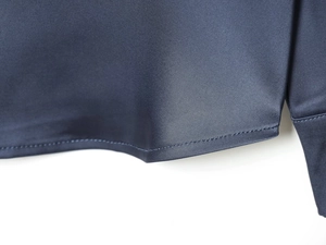 Detailed close-up of dark blue satin shirt hem with premium stitching and silky fabric