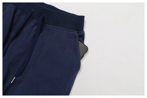 Detail of dark blue sweatpants featuring elastic drawstring waist and side pocket for phone
