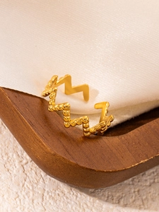 Detail of 18k gold plated stainless steel ring with wavy serrated texture on silk fabric