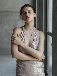 Gros plan d'un collier pendentif doré porté par une femme en robe à paillettes