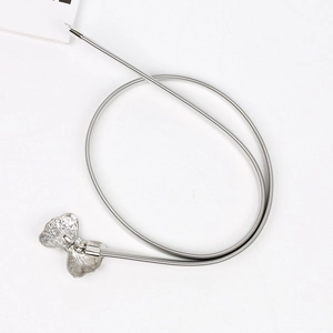 Détail de la chaîne de taille élastique argentée avec boucle papillon en strass sur fond blanc