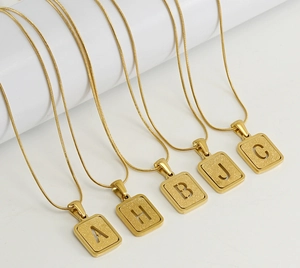 Close-up of 18K gold plated snake chain necklaces with sandblasted alphabet pendants