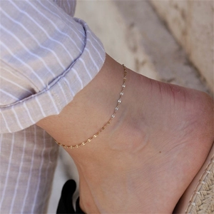Close-up of a minimalist gold lace chain anklet worn on the ankle with beach holiday vibes