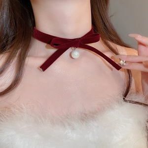 Close-up of elegant burgundy velvet bow necklace with a hanging white round pearl pendant