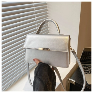 Detailed view of silver metallic shoulder bag on desk with modern office aesthetics