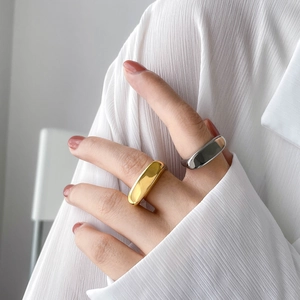 Close-up of minimalist gold and silver geometric rings on a model with a white shirt