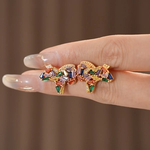 Close-up of vintage golden horse earrings with colorful zircon stones in hand
