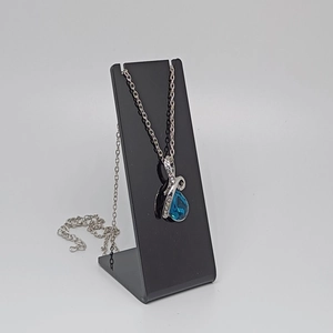Detail of silver drop necklace with blue gemstone on black acrylic display stand