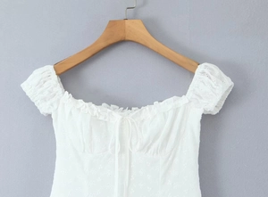 Detailed view of French lace embroidery and drawstring on a white cotton blouse