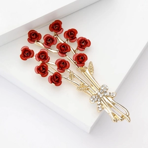 Detailed view of red enamel rose brooch with golden leaves and rhinestone bow detail