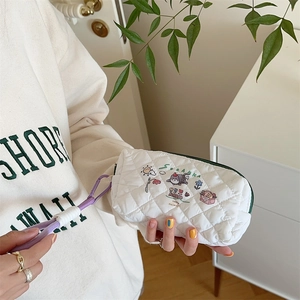 Close-up of white quilted pencil case with cute cartoon prints and green zipper detail