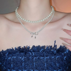 Close-up of double-layer pearl necklace with rhinestone bow pendant on female model