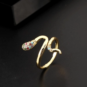 Close-up of golden snake ring with colorful zircons on a dark textured surface