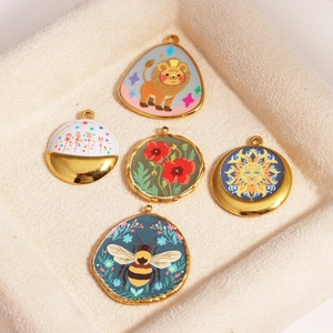 Detail of five assorted enamel floral and animal charms in a beige jewelry box