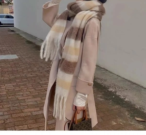 Close-up of soft plaid scarf featuring brown and yellow stripes with decorative fringe