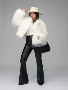 White faux fur jacket with wide-leg leather trousers and beige hat for winter fashion