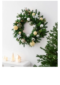 Detail of Christmas wreath with golden balls and silver bows on white wall backdrop