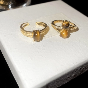 Macro shot of 18K gold plated rings featuring brown tiger eye stones and cubic zirconia
