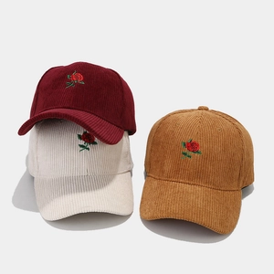 Detailed corduroy texture of baseball caps featuring delicate red rose floral embroidery