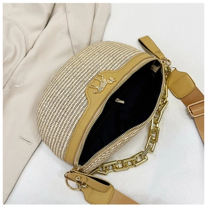 Detailed top view of straw saddle bag with khaki leather trim and gold chain link strap
