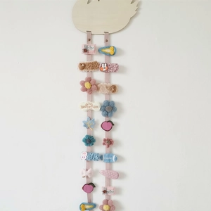 Close-up of wooden swan organizer with pink ribbons holding various kids hair clips