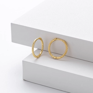 Macro shot of gold S925 sterling silver hoop earrings with twisted texture and hallmark