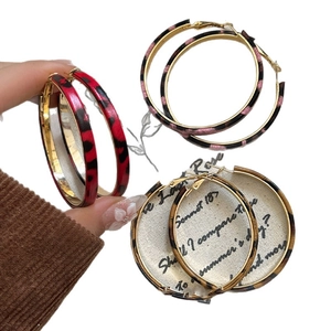 Three pairs of retro leopard print hoop earrings in red, pink, and brown color textures