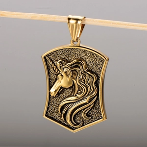Macro detail of a 18k gold-plated 304 stainless steel shield pendant with unicorn relief