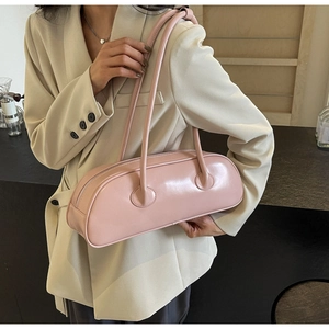 Pink cylindrical underarm bag shown with double straps on beige blazer for fashion look