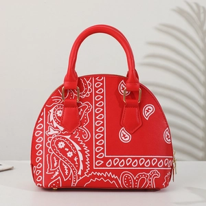 Detail view of red shell bag with white paisley pattern and gold hardware accents